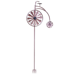 Purple metal penny farthing bicycle wind spinner with large front wheel and small rear wheel, featuring solar-powered design with ground stake base