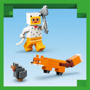 LEGO Minecraft minifigure in white shirt and yellow pants holding gray pickaxe, displayed with orange chicken and small dark chicken figures against blue background with green border