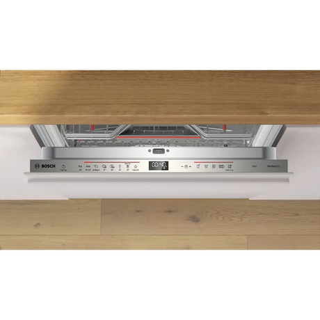 Bosch Series 6 integrated dishwasher with stainless steel control panel featuring digital display, installed under wooden countertop in modern kitchen, showing closed door with white fascia and partial view of interior rack system with red handles