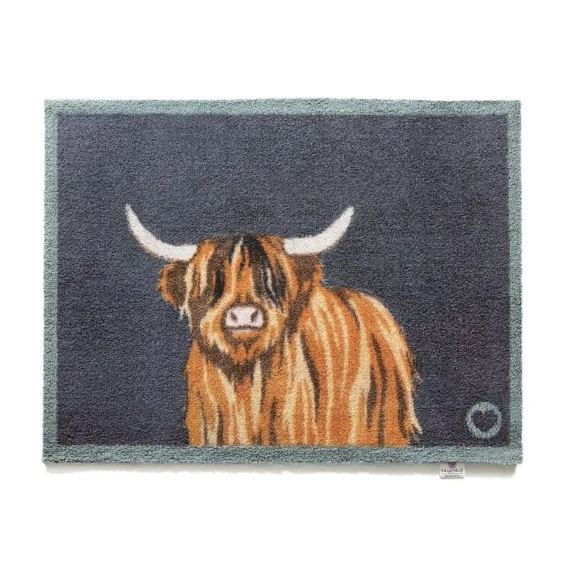 Hug Rug Highland Cow doormat 50cm x 75cm featuring a brown and orange striped Highland cattle with white horns on dark grey background with sage green border, woven natural fiber entry mat