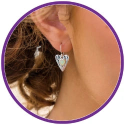 Heart-shaped earrings being worn, close-up of the ear with hair.