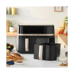 Russell Hobbs Satisfry Dual Basket Air Fryer 9 Litre in black with stainless steel accents displayed on a kitchen counter with one basket inserted and one basket removed, surrounded by fresh food ingredients and cooked items