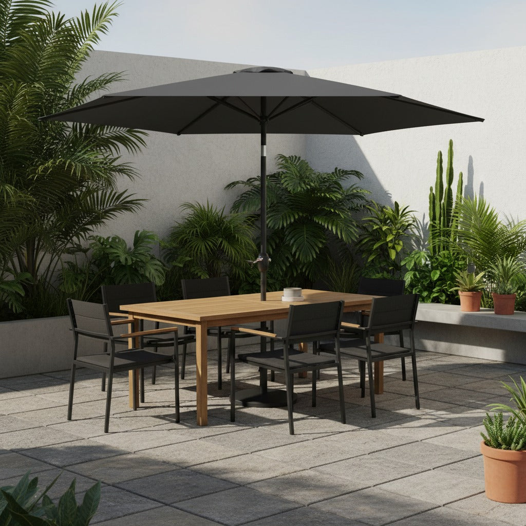 Black crank and tilt garden parasol 2.7 metre with wooden dining table and charcoal chairs on paved patio surrounded by potted green plants and tropical foliage against white wall