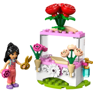 LEGO Friends Flower Stand set 30721 featuring a minifigure with black hair in colorful outfit, golden scissors, pink and white flower cart with red roses, pink blooms, cream flowers in tan pots, white daisy details, and green baseplate