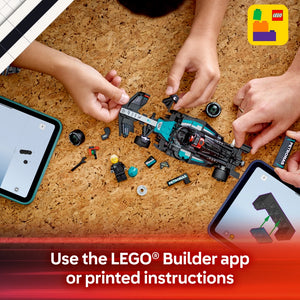 Child's hands assembling a turquoise and black LEGO Mercedes-AMG F1 W15 race car set on a cork surface with scattered LEGO pieces, minifigure, and instruction manuals on tablets nearby, demonstrating building with the LEGO Builder app