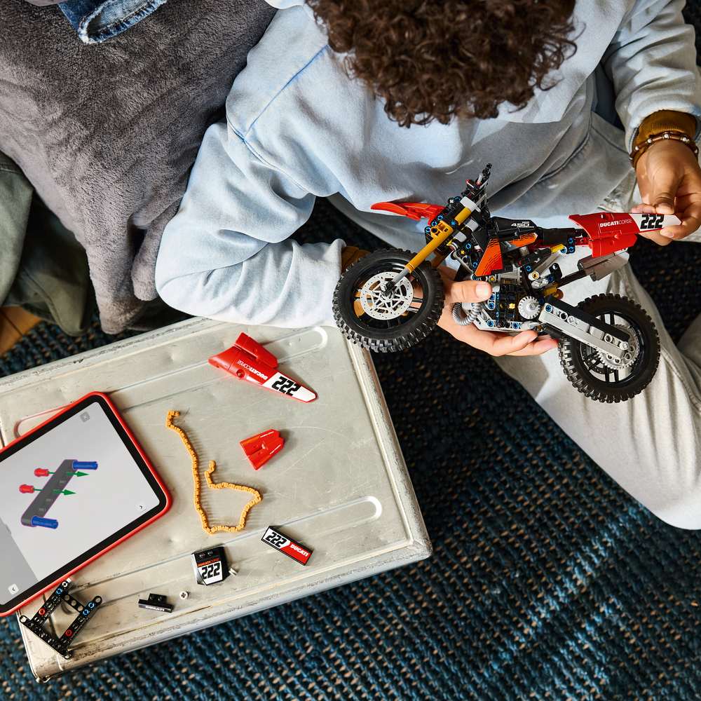 LEGO Technic Ducati Desmo450 MX Factory Motorcycle 42238 - a child building the set. 457 pieces. Ages 10+.