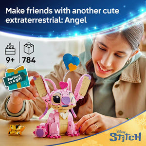 LEGO buildable Angel figure in pink and tan with blue heart-shaped head, sitting on wooden table next to small yellow companion figure, girl smiling while playing with toy, age 9+ set with 784 pieces, Disney Stitch themed construction toy