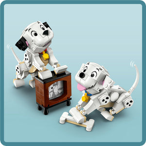 LEGO brick figures of Lucky and Penny dalmatian puppies from 101 Dalmatians, featuring white and black spotted construction with yellow collars, posed with a brown television set on a light blue background