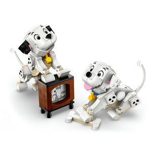 LEGO 101 Dalmatians Lucky and Penny white puppy minifigures with black spots, yellow collars, and tan accents standing on and beside a brown brick television set display