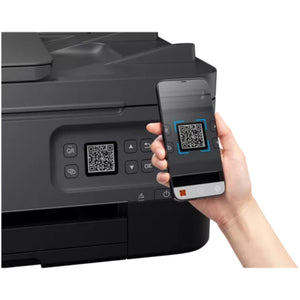 Hand holding smartphone scanning QR code on black Canon PIXMA TS7450I wireless all-in-one printer control panel with QR code button visible