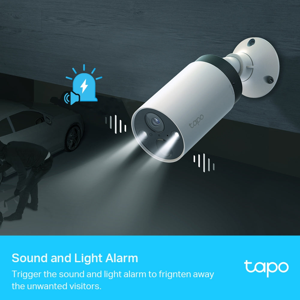 TP-Link Tapo white cylindrical security camera mounted on wall with spotlight beam illuminating parked car below, featuring sound and light alarm icons and demonstrating motion detection capabilities