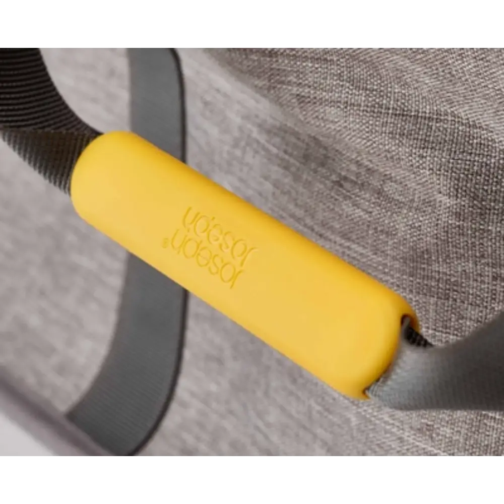 Joseph Joseph Hold All Max Laundry Basket in grey with yellow silicone handles, showing close-up detail of the ergonomic grip and fabric texture