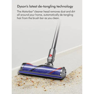 Dyson V12 Detect Slim vacuum cleaner with blue and red Motorbar cleaner head removing dust and debris from light grey floor, demonstrating automatic hair de-tangling technology