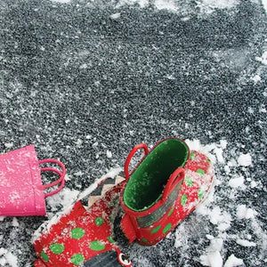 Hug Rug Doormat 50cm x 75cm in Charcoal color displayed outdoors on snowy ground with a child's red and green patterned boot and pink bucket, showing the mat's textured surface and durability in winter conditions