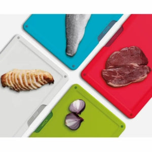 Joseph Joseph Folio Icon 4 piece chopping board set in white, turquoise, red and lime green with sliced bread on white board, raw steak on red board, sliced red onion on green board, and knife on turquoise board