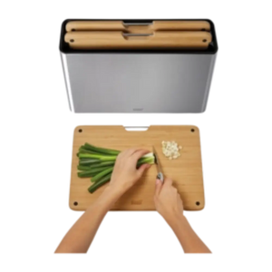 Joseph Joseph Folio Steel Bamboo three piece chopping board set showing grey steel and natural bamboo boards with hands chopping green beans on wooden board