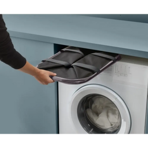 Person removing a grey fabric laundry basket from storage above a white washing machine in a light blue laundry room
