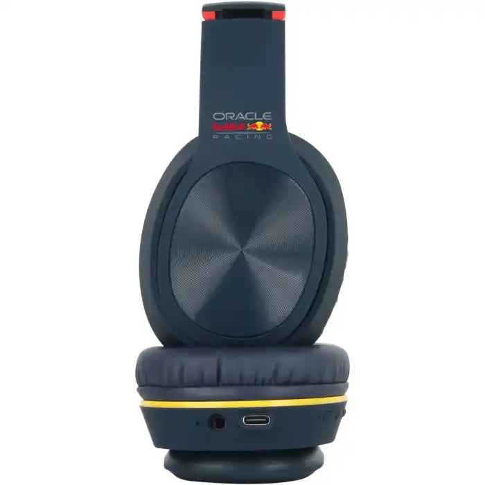 Red Bull Racing Oracle over ear Bluetooth headphones in dark blue with red accents, featuring a metallic silver circular ear cup design, yellow accent band around the ear cup, and USB-C charging port visible on the base