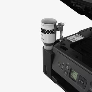 Coffee cup with polka dot sleeve being used with a printer on a white background