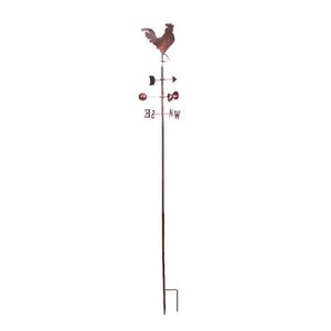 Rustic copper rooster weather vane with directional cardinal points (N, S, E, W) mounted on tall metal pole with ground stake