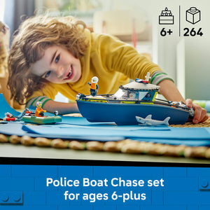 Young child in yellow shirt playing with LEGO Police Boat Chase set featuring blue and yellow police boat with minifigures, shark toy, and sandy beach play mat with rope border, 264 pieces, ages 6 plus