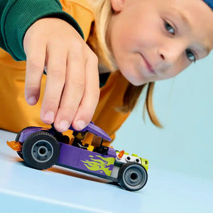 Young child playing with LEGO Hot Rod 60485, a purple and yellow buildable toy car with flame details and black wheels, against a light blue background