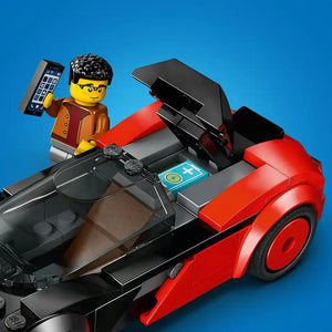 LEGO EV Supercar set 60486 featuring a red and black electric sports car with opening doors, a yellow minifigure with black hair wearing orange and red jacket holding a mobile phone, black steering wheel, blue instruction manual, and gray interior details against a bright blue background