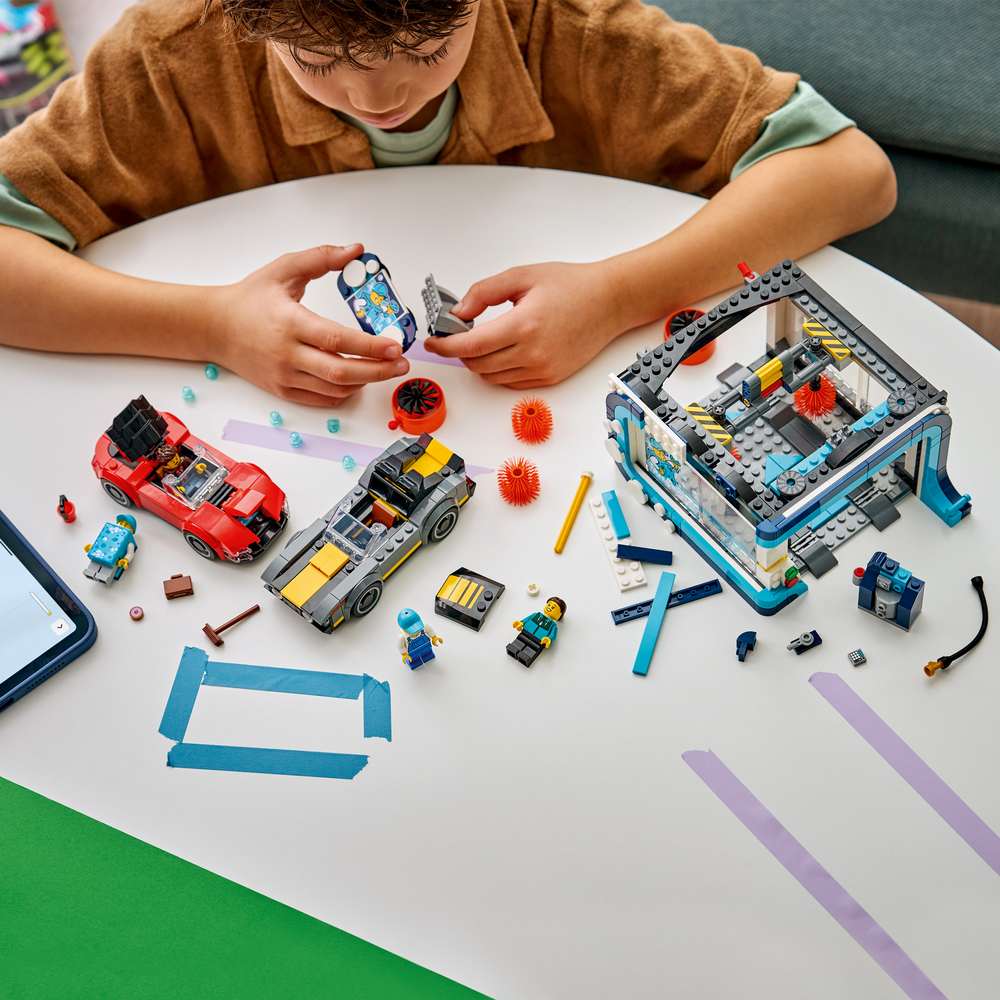 LEGO City Drive-Through Car Wash 60497 child building the set, assembling the blue and grey car wash structure with bricks laid out alongside