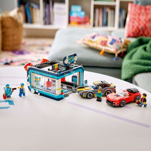 LEGO City Drive-Through Car Wash 60497 displayed in a home living room setting, complete with both toy cars and minifigures