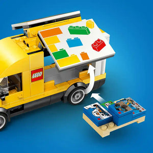 LEGO The LEGO Van 60500 set featuring a bright yellow construction vehicle with opening doors, roof-mounted display board showing colorful LEGO bricks in red, green, blue, orange and yellow, authentic LEGO branding on the side, accompanied by instruction manuals on a tan baseplate against a blue background