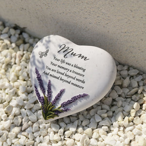 White ceramic heart-shaped memorial stone with purple lavender flowers and butterfly design, engraved with "Mum" and tribute message, displayed on decorative white and grey pebbles