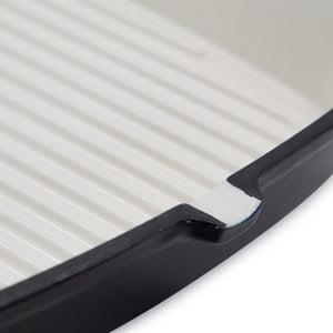 Close-up of a black cast iron griddle pan handle showing ridged cooking surface and curved grip detail