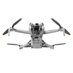 DJI Mini 4 Pro drone viewed from above showing grey and white body with four black propellers tipped in orange, central camera gimbal, and RC 2 controller base