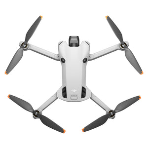 DJI Mini 4 Pro RC 2 drone viewed from above showing white body with gray arms, four black propellers with orange tips, central camera gimbal, and status indicator lights