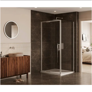 Modern bathroom featuring a chrome-framed 6 Series Sleek infold shower door with clear glass panels installed in a corner configuration, set against dark brown marble-effect wall tiles, white shower tray, complemented by a wooden slatted vanity unit with terracotta basin, round LED backlit mirror, and cream vertical wall tiles