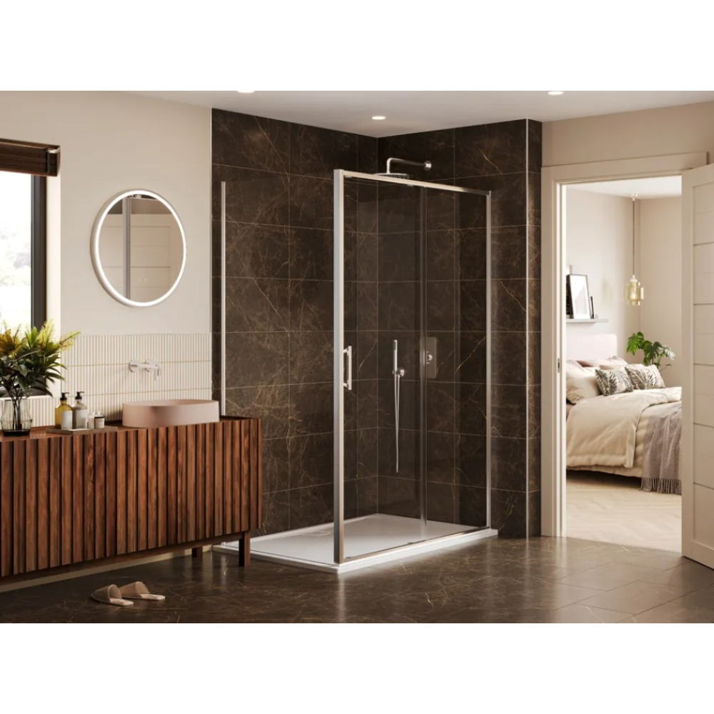 Modern luxury bathroom featuring a Merlyn 6 Series chrome sliding shower enclosure with dark marble-effect tiles, adjacent to a wooden vanity unit with circular illuminated mirror, cream and beige walls, and view into bedroom beyond