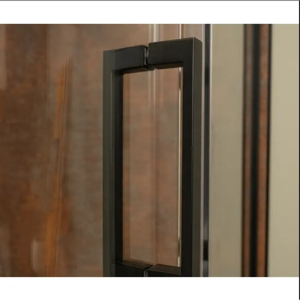 Modern rectangular door pull handle in matte black finish mounted on a glass shower enclosure door, featuring clean geometric lines and contemporary minimalist design with warm wooden tones visible in the background