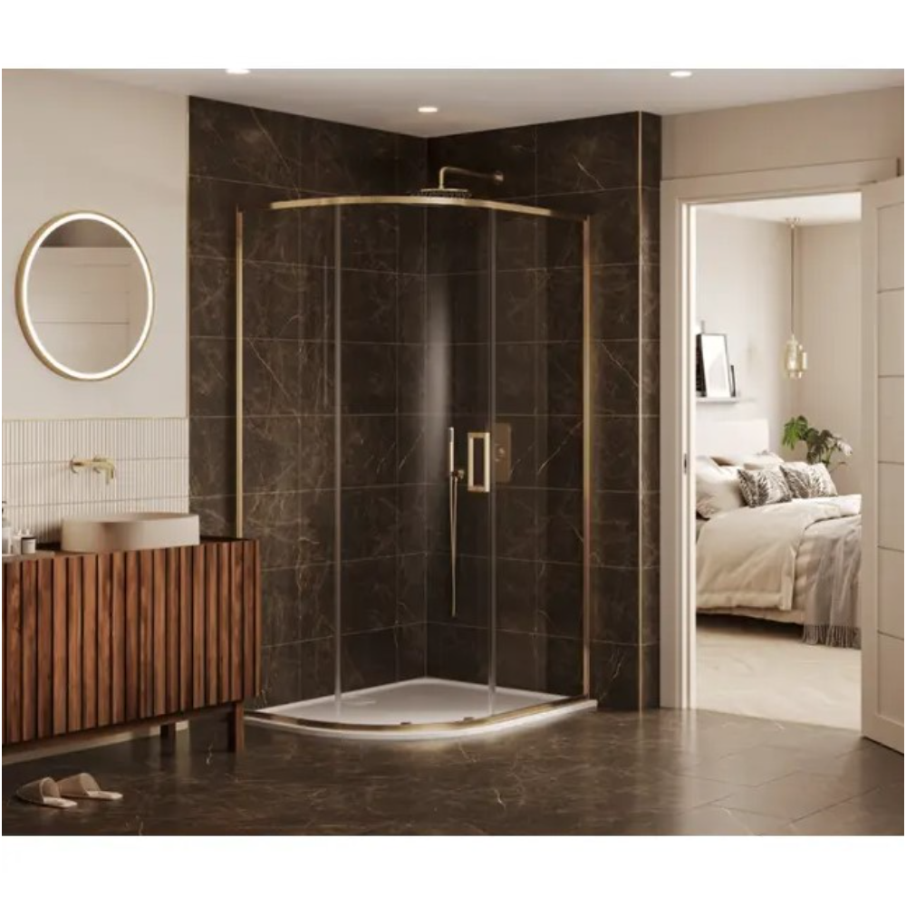 Modern quadrant shower enclosure with curved glass doors and brushed brass frame, featuring a white shower tray, large rainfall showerhead, and handheld shower attachment, installed in a luxurious bathroom with dark brown marble-effect wall tiles, matching floor tiles, wooden slatted vanity unit with round vessel sink, backlit circular mirror, and view through doorway to adjoining bedroom