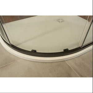 Quadrant shower enclosure base with curved glass sliding doors featuring black frame and rollers, white low-profile shower tray with square drain cover, installed on beige tile flooring in modern bathroom setting