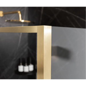 Merlyn 6 Series Sleek brushed brass sliding shower door frame detail showing horizontal handle and vertical post against dark background with white candles visible through glass panel
