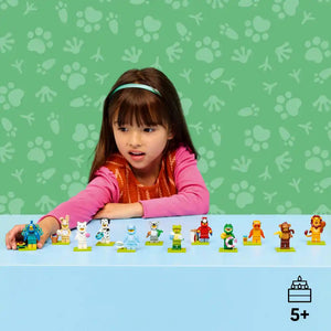 Young child with brown hair and light blue headband wearing pink long-sleeved shirt examining a lineup of colorful LEGO minifigures from Animals Series 28 against green patterned background, with 5+ age rating indicator