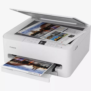 Canon TS6550i white all-in-one wireless inkjet printer with open scanner lid showing colorful travel magazine page being scanned, and printed photo exiting from output tray below