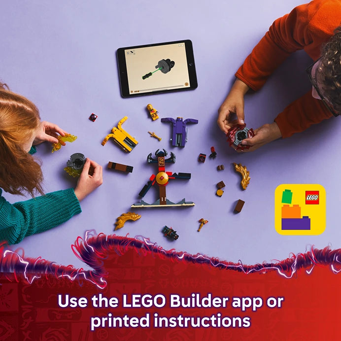 Overhead view of two children's hands assembling LEGO Dragon Spinjitzu Battle Pack 71826 on a purple surface, with scattered colorful LEGO pieces including yellow and purple minifigures, a tablet displaying building instructions, and the LEGO app logo in bottom right corner