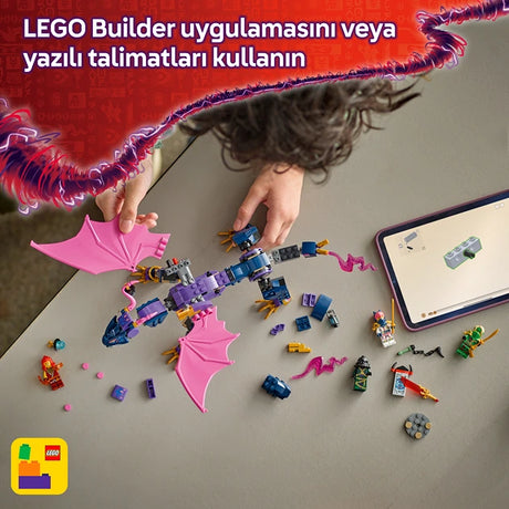 Child's hands building a colorful LEGO dragon with purple and blue bricks and pink fabric wings on a gray surface, with a smartphone displaying building instructions and scattered LEGO pieces nearby