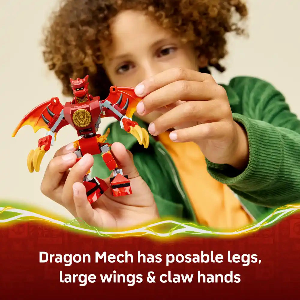 Child with curly brown hair wearing a green sweater holding a red and yellow LEGO Ninjago dragon mech toy with posable legs, large wings and claw hands against a cream background