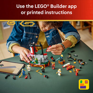 Child building LEGO Ninjago set with minifigures and structures on green surface while using LEGO Builder app on tablet, featuring red and white ninja tower, colorful minifigures, and scattered LEGO pieces