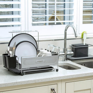 Blackmoor Deluxe stainless steel and black dish drainer rack on kitchen countertop next to chrome faucet, holding white plates, bowls and utensils with draining tray