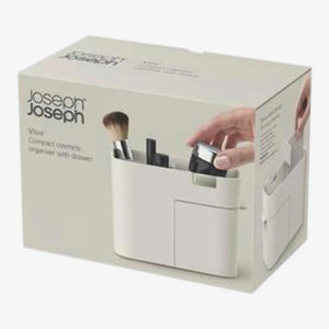 Joseph Joseph Viva white cosmetic makeup organizer with drawer showing brushes and beauty products inside, displayed against cream product packaging box