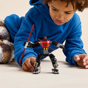 Young child in blue hoodie playing with LEGO Darth Maul Mech set 75411, featuring red and black buildable robot figure with lightsaber, displayed on white surface