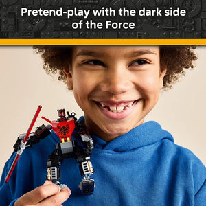 Young child with curly hair smiling while holding a red and black LEGO Darth Maul mech figure with red lightsaber, wearing a blue hoodie against a neutral background